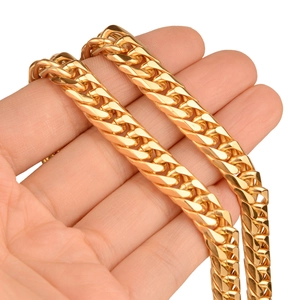 Macro shot of thick gold Cuban link chain necklace held by hand showing metallic shine