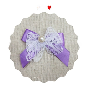 Detail of purple satin bow with white lace trim and a central pearl accent