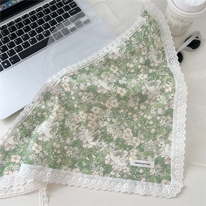 Detailed macro of green floral cotton neck scarf with delicate white lace border trim