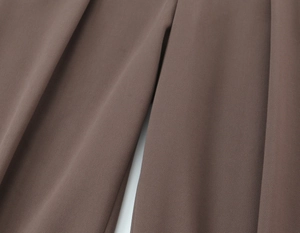 Détail macro du tissu marron montrant la texture fine et le drapé naturel du costume