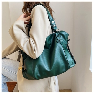 Detail view of a large dark green canvas tote bag showing shoulder strap and side D-ring hook