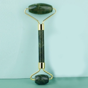 Detail of dual-head jade facial roller with green stone and golden metal frame