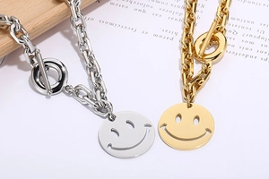Detail of silver and gold curb chains with smile face charms and toggle clasps