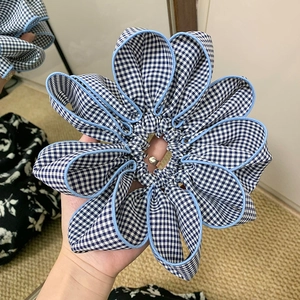 Detail of blue and white checkered fabric scrunchie with layered flower petal structure
