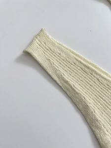 Detailaufnahme der cremefarbenen Strickbündchen mit feiner vertikaler Rippenstruktur