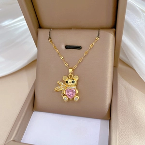 Gold teddy bear necklace with pink heart zircon pendant in a beige jewelry box