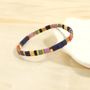 Close-up of colorful Tila bead bracelet with enamel finish on white ceramic stand