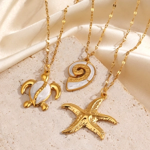 Golden sea turtle, starfish and conch shell pendant necklaces on elegant beige silk fabric