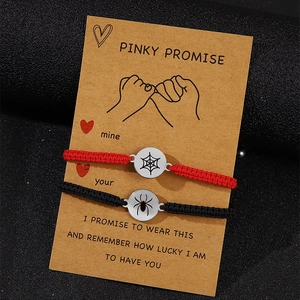 Detail of red and black woven couple bracelets with spider and web charms on card
