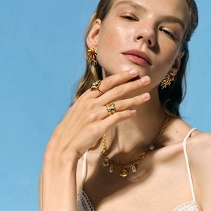 Golden ocean jewelry set featuring coral earrings and shell rings on a blue background