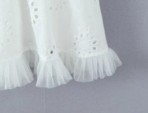 Vue détaillée de la broderie florale blanche et de l'ourlet en tulle plissé