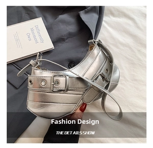 Close-up of metallic silver crescent bag featuring industrial metal eyelets and buckles