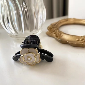 Mini camellia hair claw clip in black and white with gold accents for elegant styling