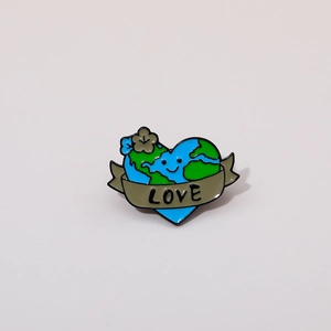 Close-up of a heart-shaped earth cartoon badge with a flower and LOVE banner