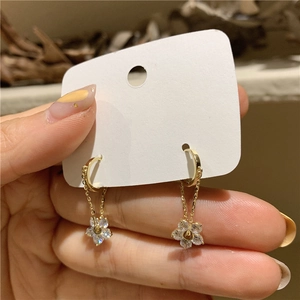 Detail of gold flower drop earrings with sparkling rhinestones and delicate tassel chains