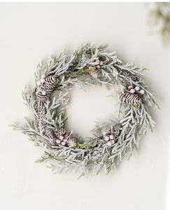 Close-up of frosted Christmas wreath with pine cones and red berries on white background