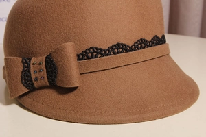 Detailed close-up of wool fedora featuring black lace ribbon and a bow with beads