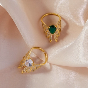 Bohemian adjustable golden wing rings with clear and emerald cubic zirconia on beige silk