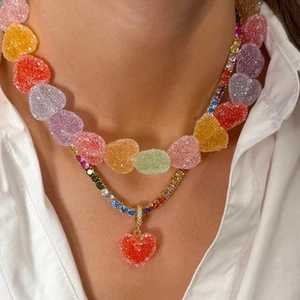 Detail showing gold tennis necklace with multicolor gems and candy-colored heart bead chain