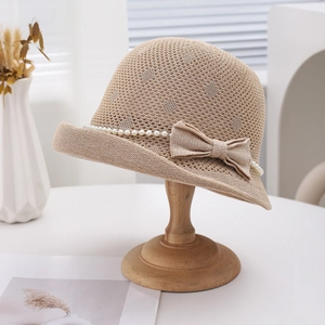 Chapeau de soleil élégant en maille beige avec perles et nœud sur un support en bois