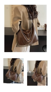 Detailed view of a brown soft leather hobo bag with silver chain on a beige blazer