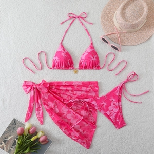 Detailed flat lay of three-piece hibiscus print bikini with matching sarong and metal flower