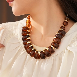 Détail macro d'un collier vintage en résine ambrée avec des accents dorés chic