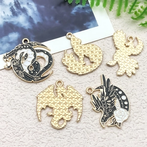 Detail of five alloy charms including black and white enamel dragon and crescent moon designs