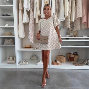 Détail d'une robe crème élégante avec texture florale 3D et manches bouffantes stylées