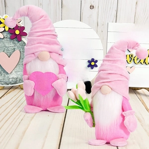 Detail view of pink Mother's Day gnomes holding heart and tulips against wooden background