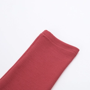 Détail du poignet en maille rouge montrant la couture haute densité et la texture côtelée