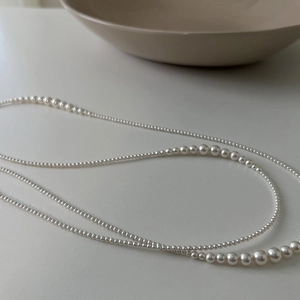 Elegant French style long pearl necklace with gradient white pearls on minimalist background
