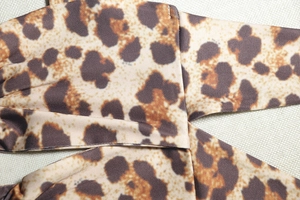 Gros plan du tissu imprimé léopard montrant les coutures fines et la texture du costume