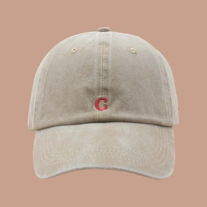 Macro shot of embroidered red letter C on washed sand-colored vintage cotton baseball cap