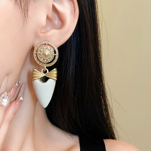 Macro detail of vintage gold bow earrings with heart pendant and sparkling zircons