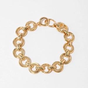 Pulsera de cadena gruesa bañada en oro con eslabones circulares sobre fondo blanco