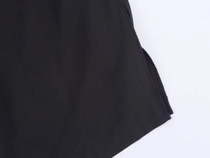 Detaillierte Nahaufnahme eines schwarzen Neckholder-Oberteils mit Saumschlitz und Naht