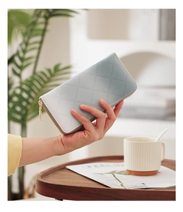 Close-up of light blue gradient quilted long wallet with golden zipper detail
