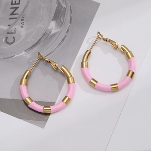 Detail of pink enamel and gold-plated titanium steel hoop earrings on stylish magazine