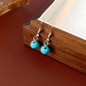 Détail de boucles d'oreilles en perles de turquoise et crochets en argent dans un écrin