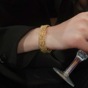 Detail of multi-layer gold plated beaded bracelet with spiral texture on woman wrist
