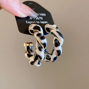 Detail of round leopard print resin hoop earrings with twisted gold metal wire design