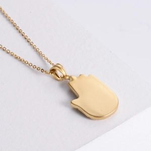 Gothic 18K gold stainless steel Hamsa hand pendant necklace on a clean white textured background