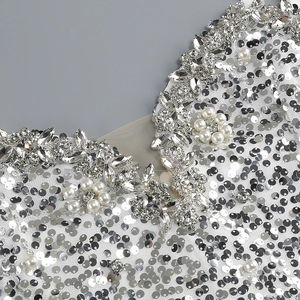 Dettaglio di paillettes argento, perle e strass sullo scollo di un mini abito da festa