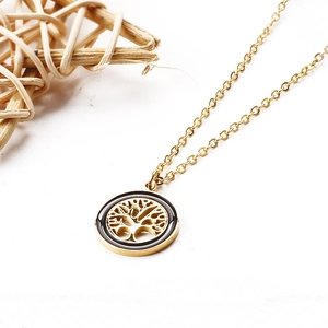 Close-up of golden Tree of Life necklace with black enamel detail on white background