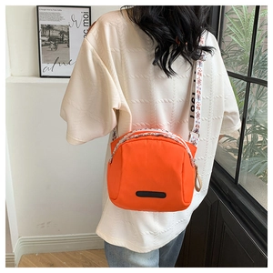 Orange nylon crossbody bag with ethnic patterned strap shown on a female model