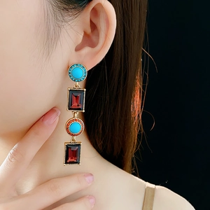 Vintage bronze drop earring with turquoise and ruby stones worn by a model