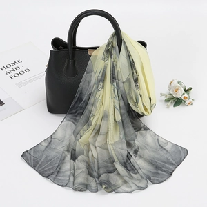 Detail of floral chiffon scarf with abstract leaf patterns draped over a black handbag