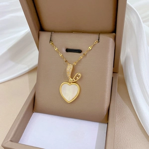 Elegant gold heart pendant necklace with white shell inlay and diamonds in a jewelry box