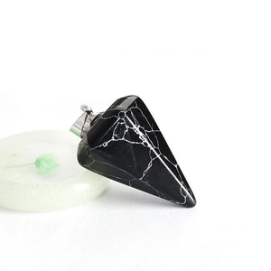Vista macro de un colgante de piedra negra facetada con vetas blancas y cierre plata